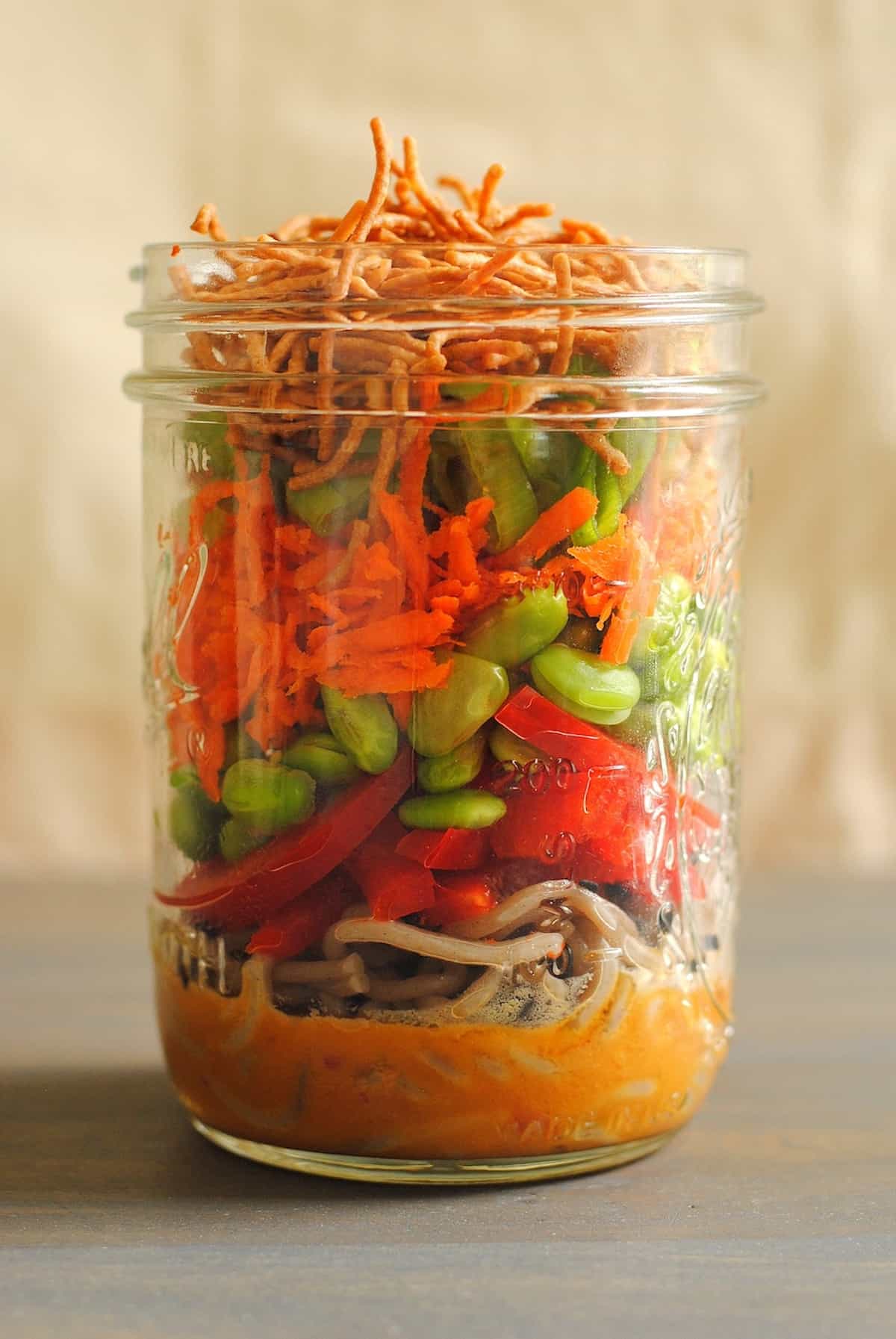 These Asian Noodle Salad Jars are a portable, colorful and healthful lunch that will get you through the work week, deliciously. | foxeslovelemons.com Glass mason jar filled with layers of dressing, noodles and vegetables.