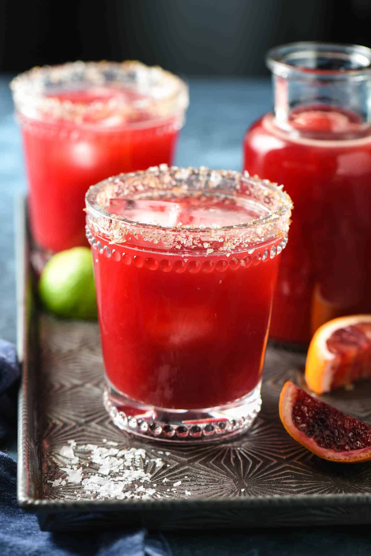 Blood orange margaritas on serving tray with salt garnish.