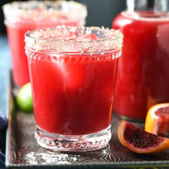 Blood orange margaritas on serving tray with salt garnish.