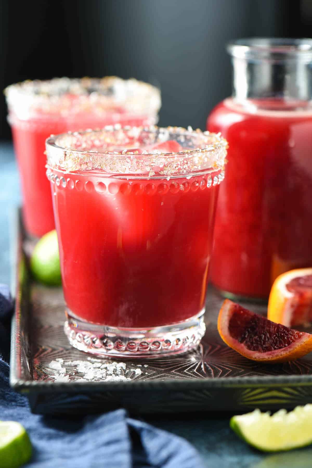 This Blood Orange Margarita recipe is sweetened with honey, and comes together in 5 minutes, with just 4 ingredients. | foxeslovelemons.com Bright red cocktail in glass garnished with salt and sugar.