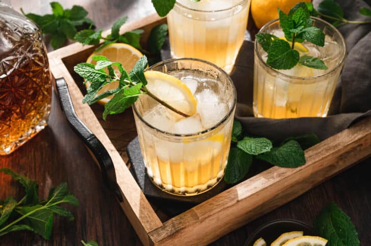 A tray filled with bourbon smash drinks garnished with mint sprigs.