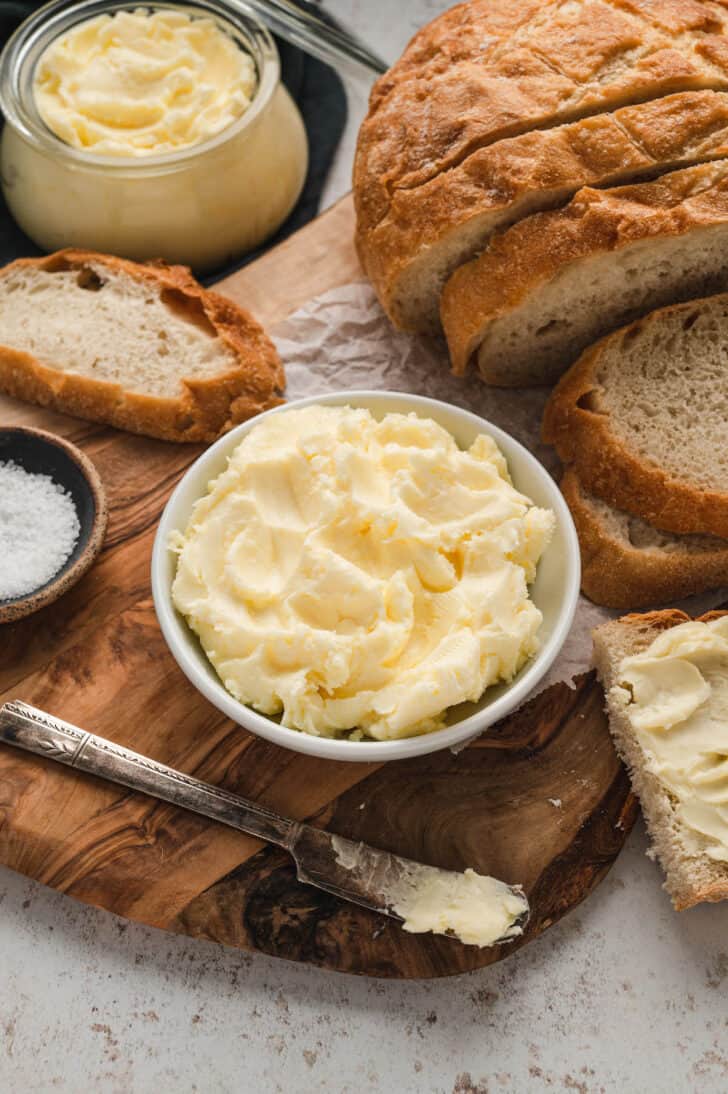 Bread spread with homemade butter on a rustic wooden cutting board.