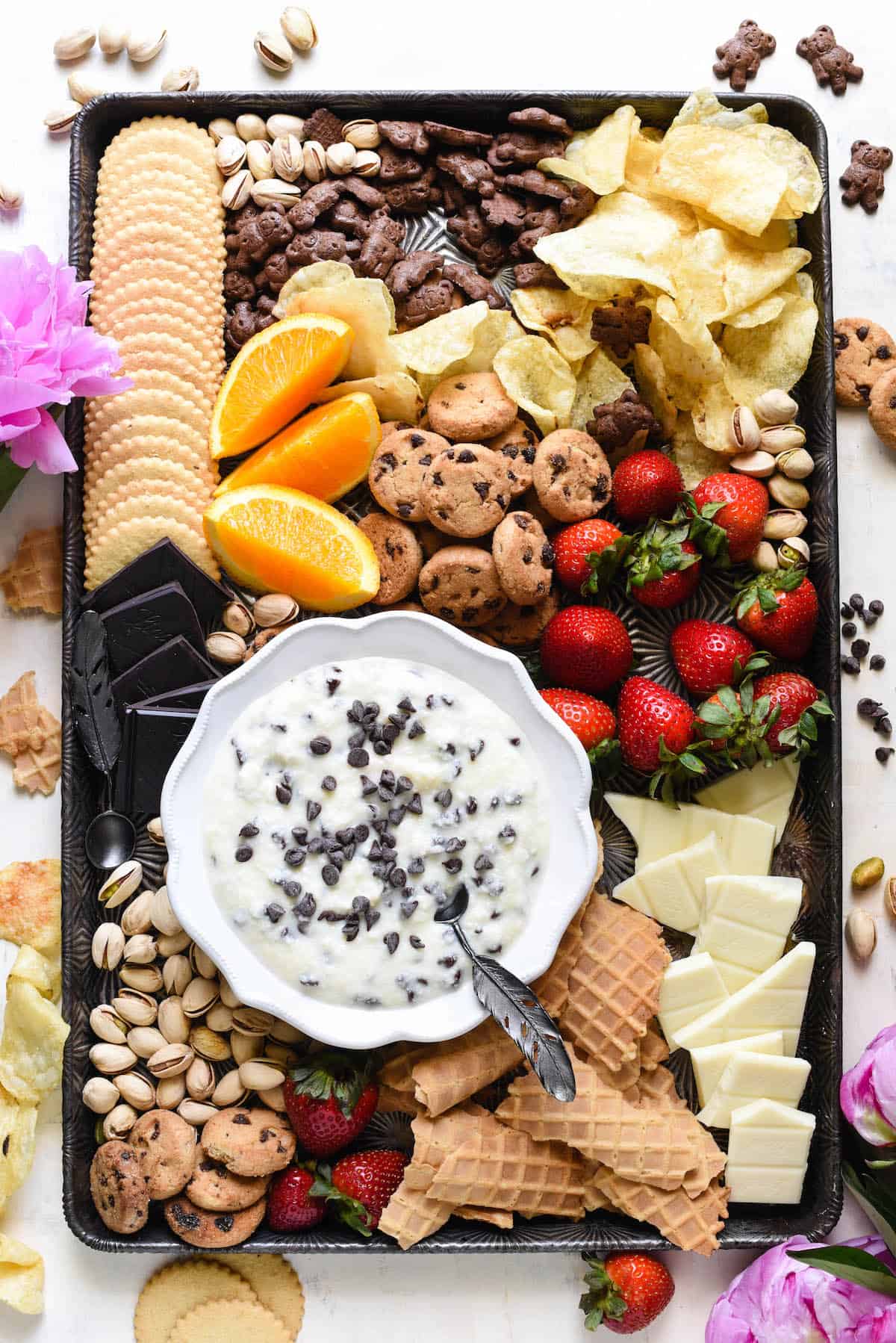 Celebrate every day with this Cannoli Dip. It's so easy, you can whip it up on a whim. Just five ingredients and five minutes. Serve with sweet and salty dippers of your choice. | foxeslovelemons.com Overhead shot of large pan with bowl of cannoli dip and cookies, fruit, nuts and potato chips for dipping.