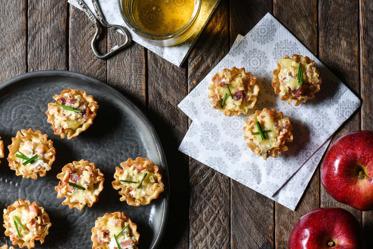 Update your holiday snack spread with these Cheesy Apple & Bacon Phyllo Cup Appetizers - a modern take on a cheeseball and crackers. | foxeslovelemons.com Party scene with phyllo cup appetizers, cocktail and fresh apples.