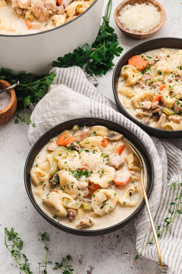 Black bowls filled with creamy chicken tortellini soup.