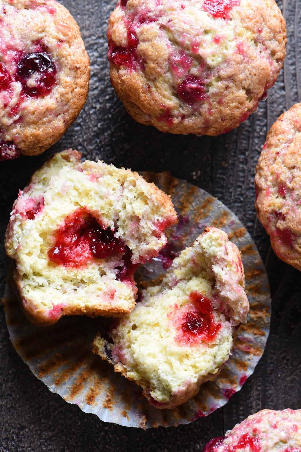 These Cranberry Sauce Muffins are the most delicious way to use up leftover cranberry sauce after Thanksgiving. You can whip these up in just a few minutes! | foxeslovelemons.com Overhead photo of cranberry muffins, with one broken in half to reveal inside.