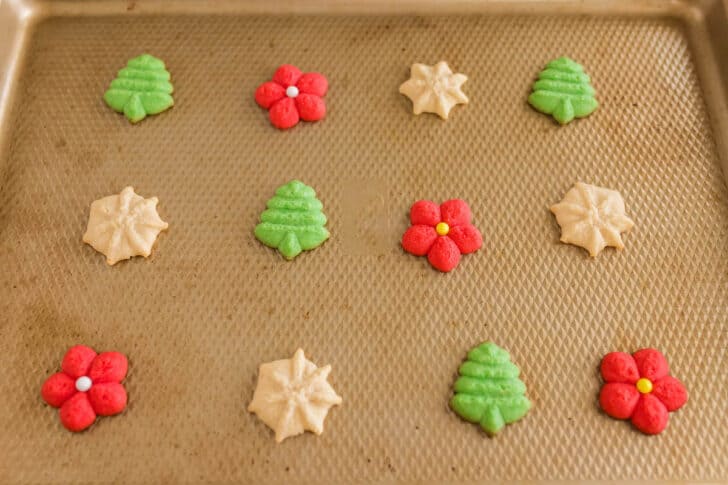 Christmas spritz cookies on a textured gold pan.