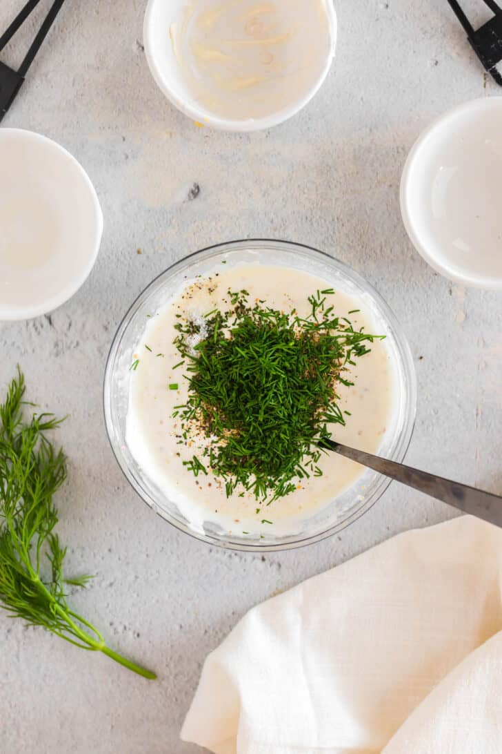 Dill sauce being stirred together in a glass bowl.