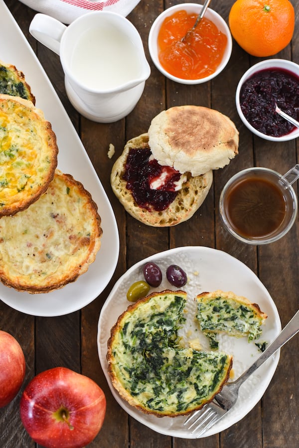 Hosting a brunch get-together and not sure where to begin? These 7 Tips for an Easy Brunch Buffet will have you feeling like a pro without breaking a sweat. | foxeslovelemons.com Overhead shot of brunch party table filled with mini quiches, olives, coffee, breakfast breads and spreads, salad and fruit.