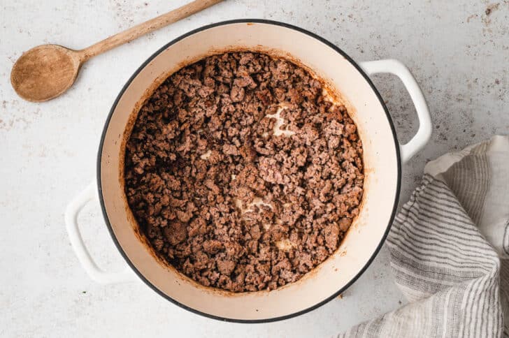 Cooked ground beef in a white Dutch oven.