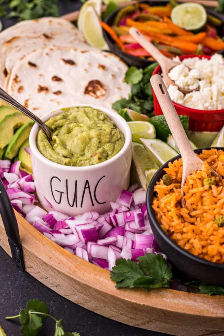 Fajita bar toppings including guacamole, cotija cheese and chopped red onion.