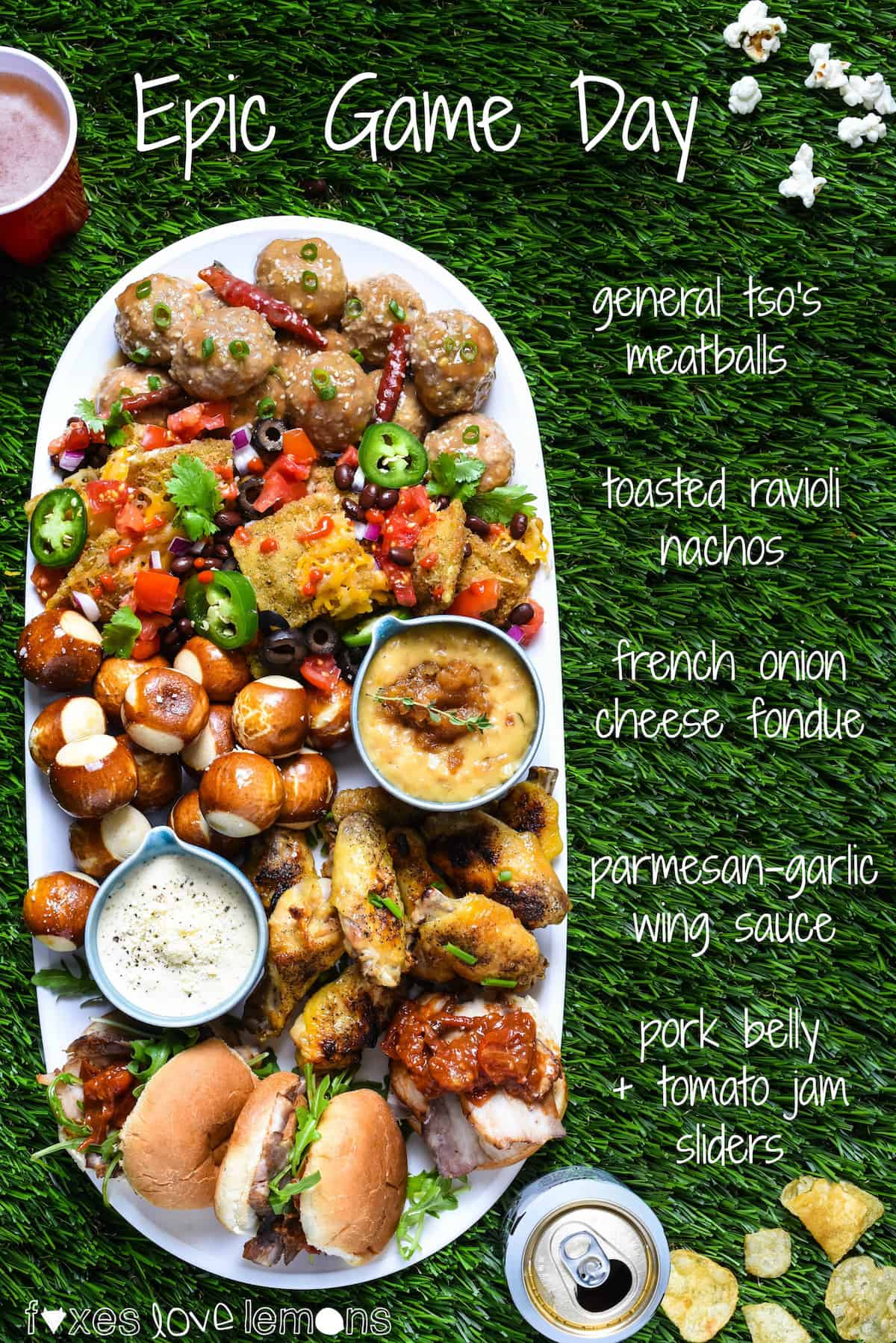 Astroturf topped with various types of tailgating food, including sliders, nachos, chicken wings cheese dip and meatballs.