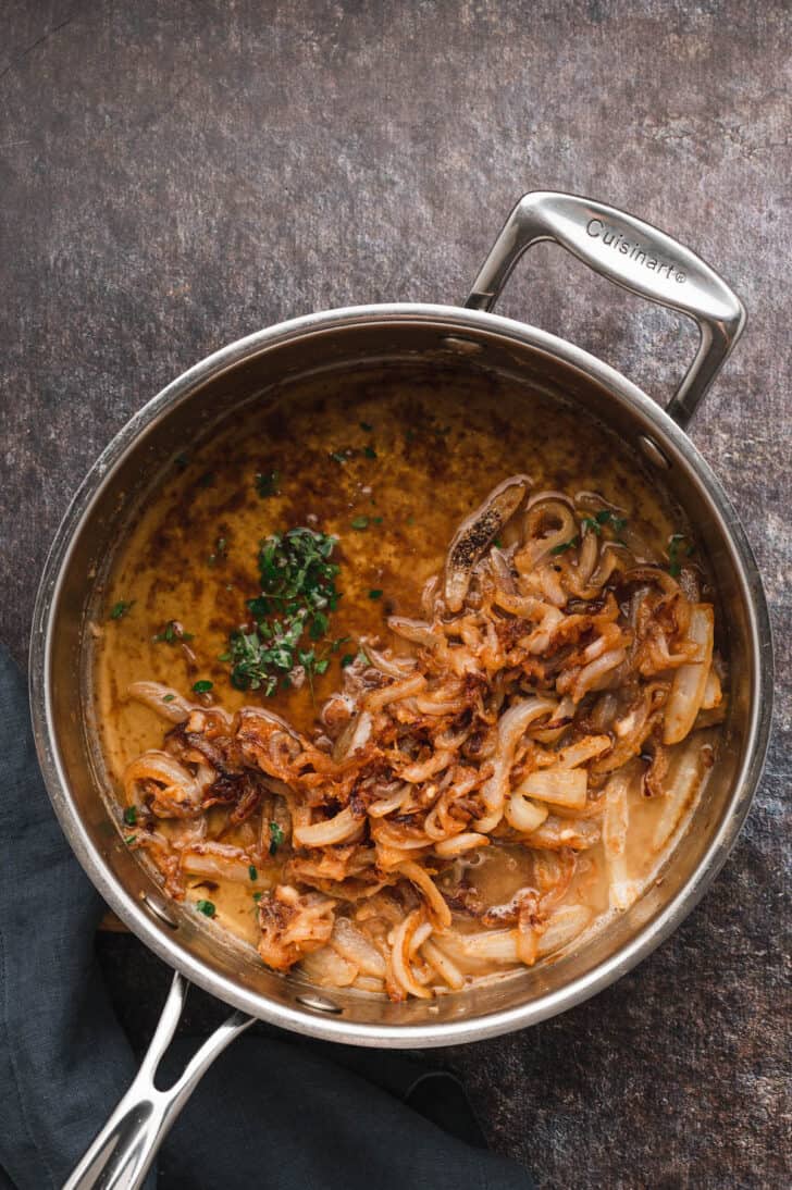 Sauteed onions with thyme in a stainless steel skillet.