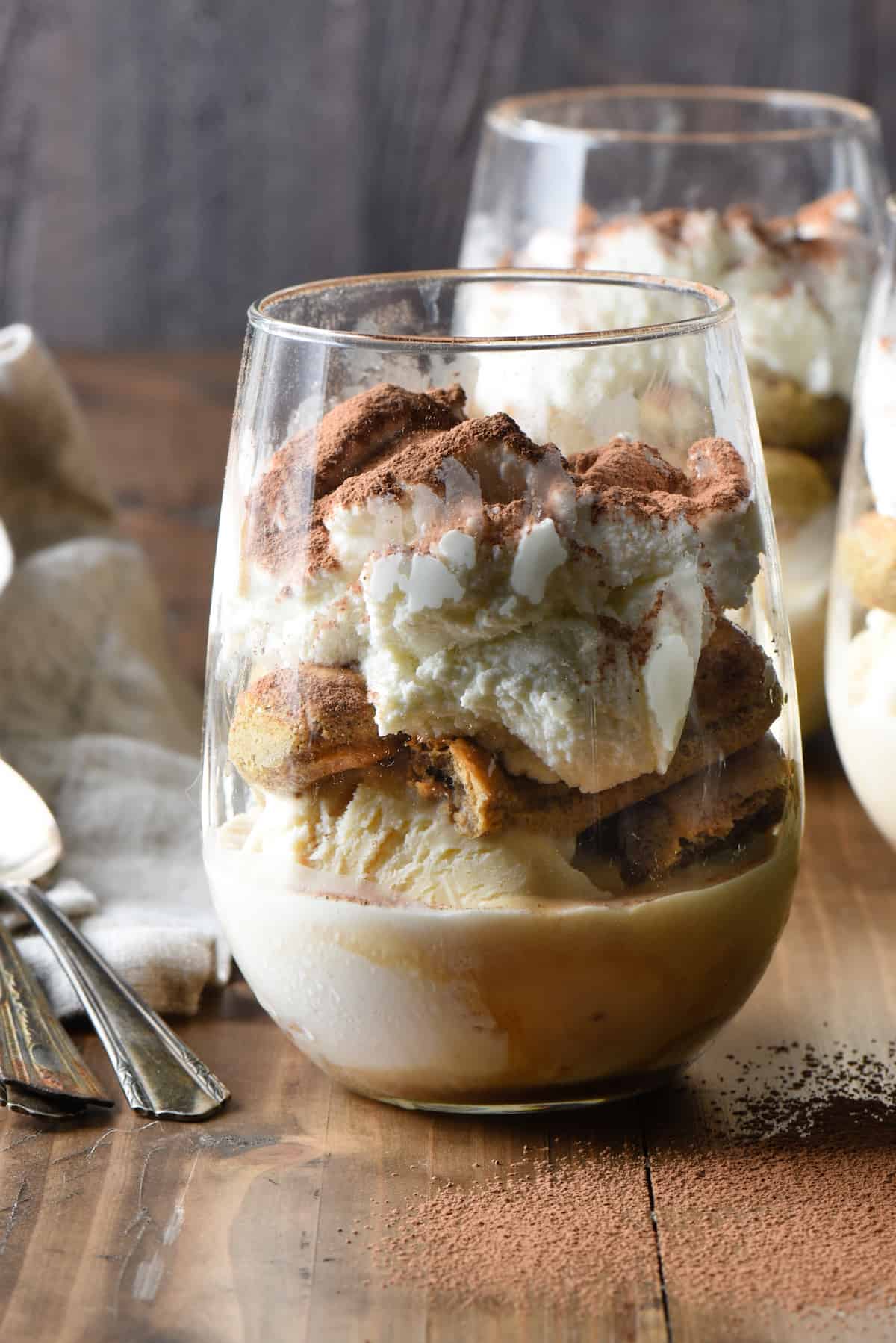 These Frozen Tiramisu Cups are a decadent five minute treat in a glass! Layers of coffee-soaked lady fingers, ice cream and mascarpone whipped cream. | foxeslovelemons.com Frozen tiramisu cup made in a stemless wine glass.