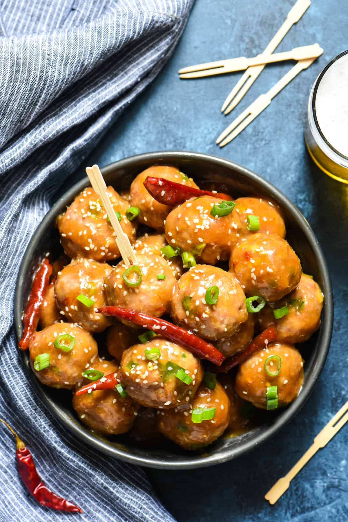 General Tso's Meatballs - Pork meatballs are slathered in tasty General Tso's sauce in this fun party recipe! | foxeslovelemons.com Chinese meatballs being served in a party tablescape, with toothpicks and beer.