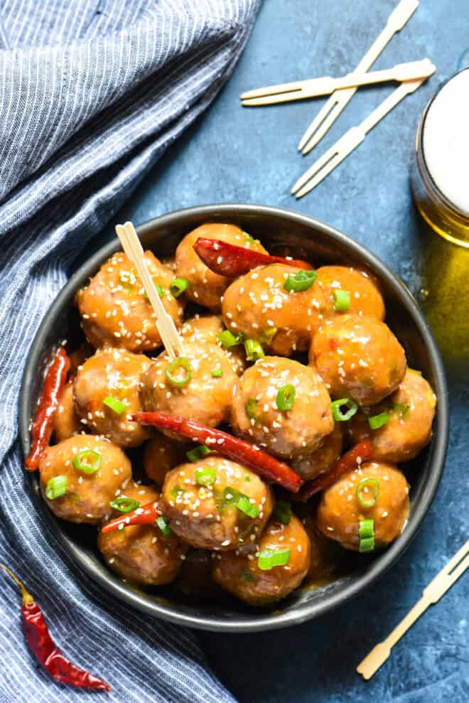 General Tso's meatballs being served in a party tablescape, with toothpicks and beer.