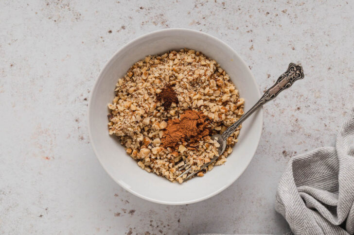 A small white bowl filled with chopped walnuts and spices.