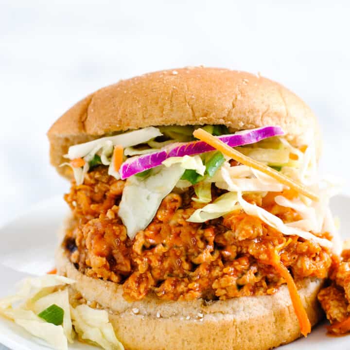 Wheat hamburger bun filled with orange hued chicken sloppy joe mixture and coleslaw.