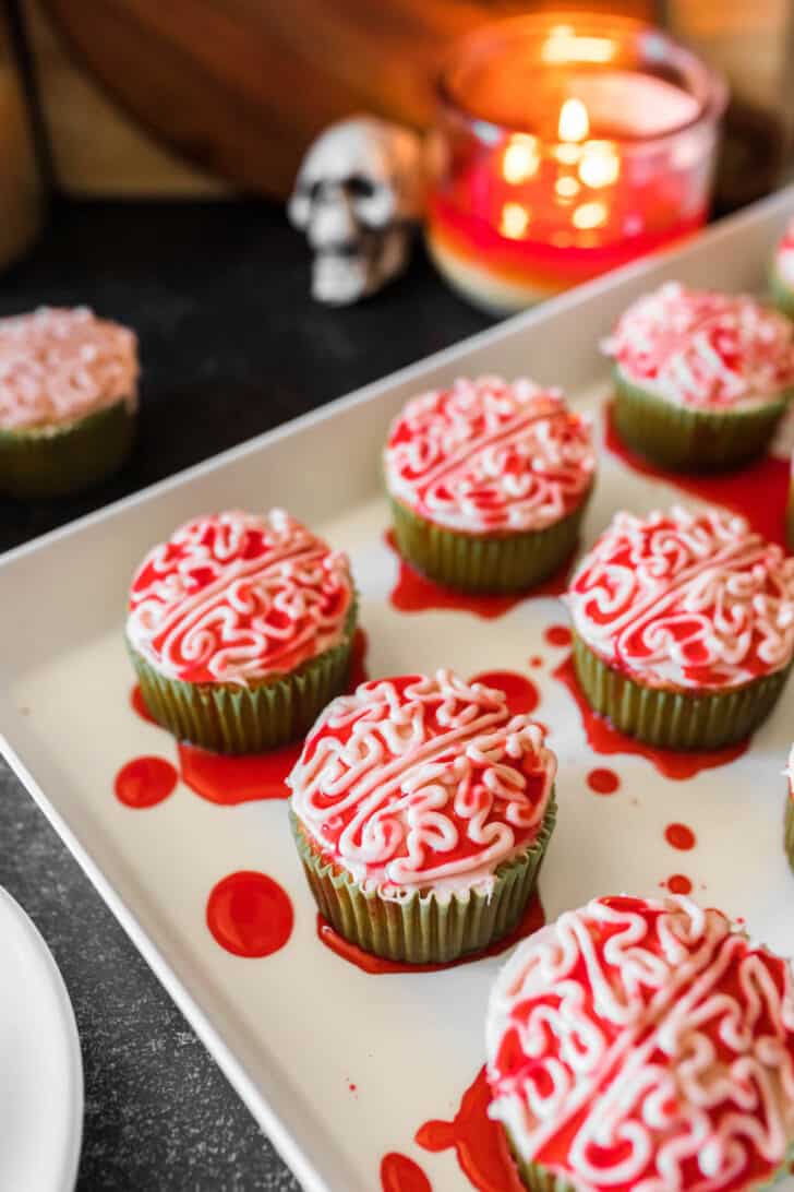 Halloween cupcakes piped with frosting to look like bloody zombie brains, on a white platter.