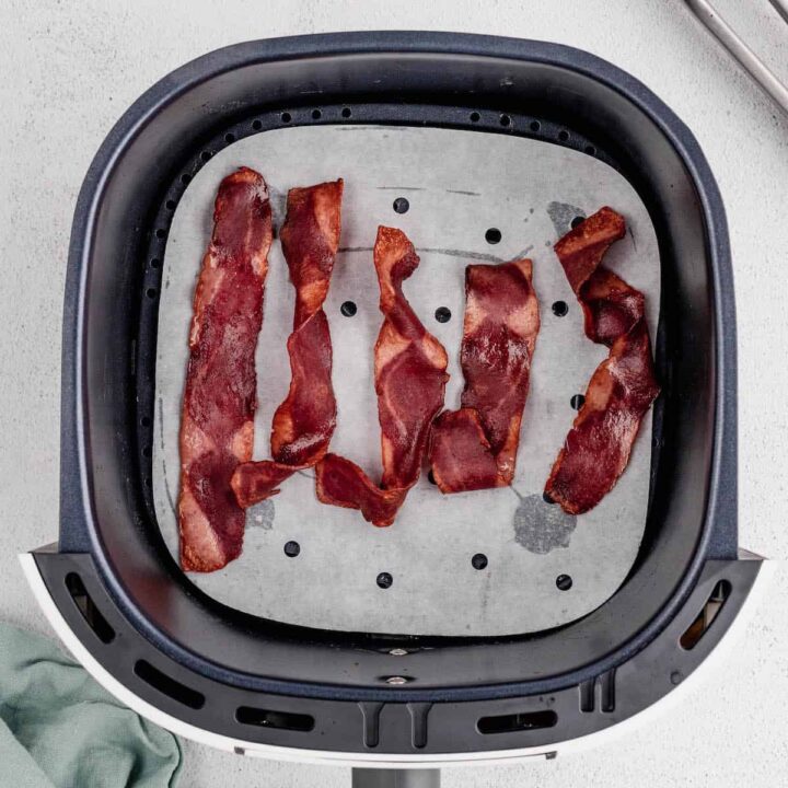 Five slices of turkey bacon in an air fryer basket.