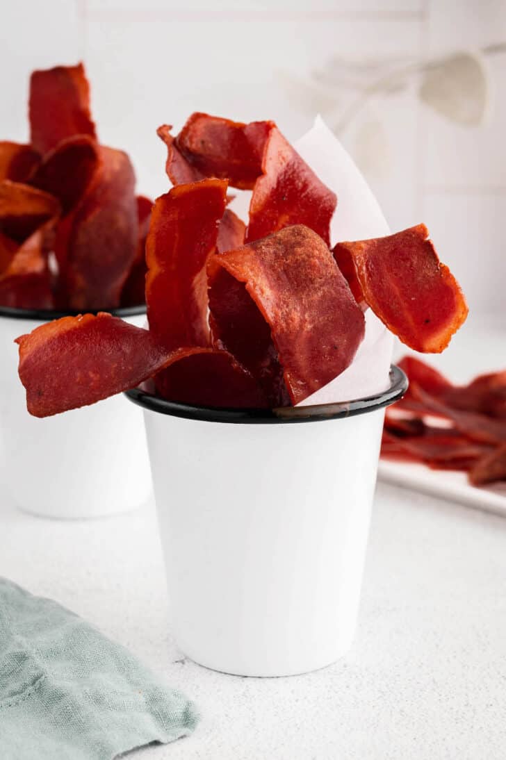 Crispy turkey bacon in a white enamel cup.