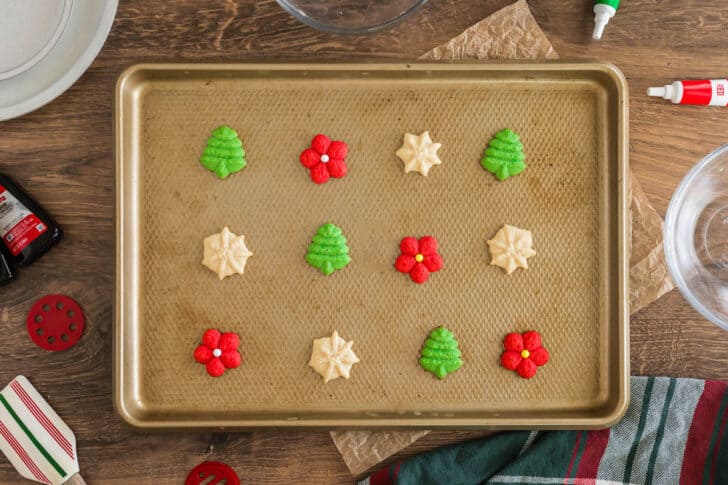 Christmas spritz cookies on a textured gold pan.