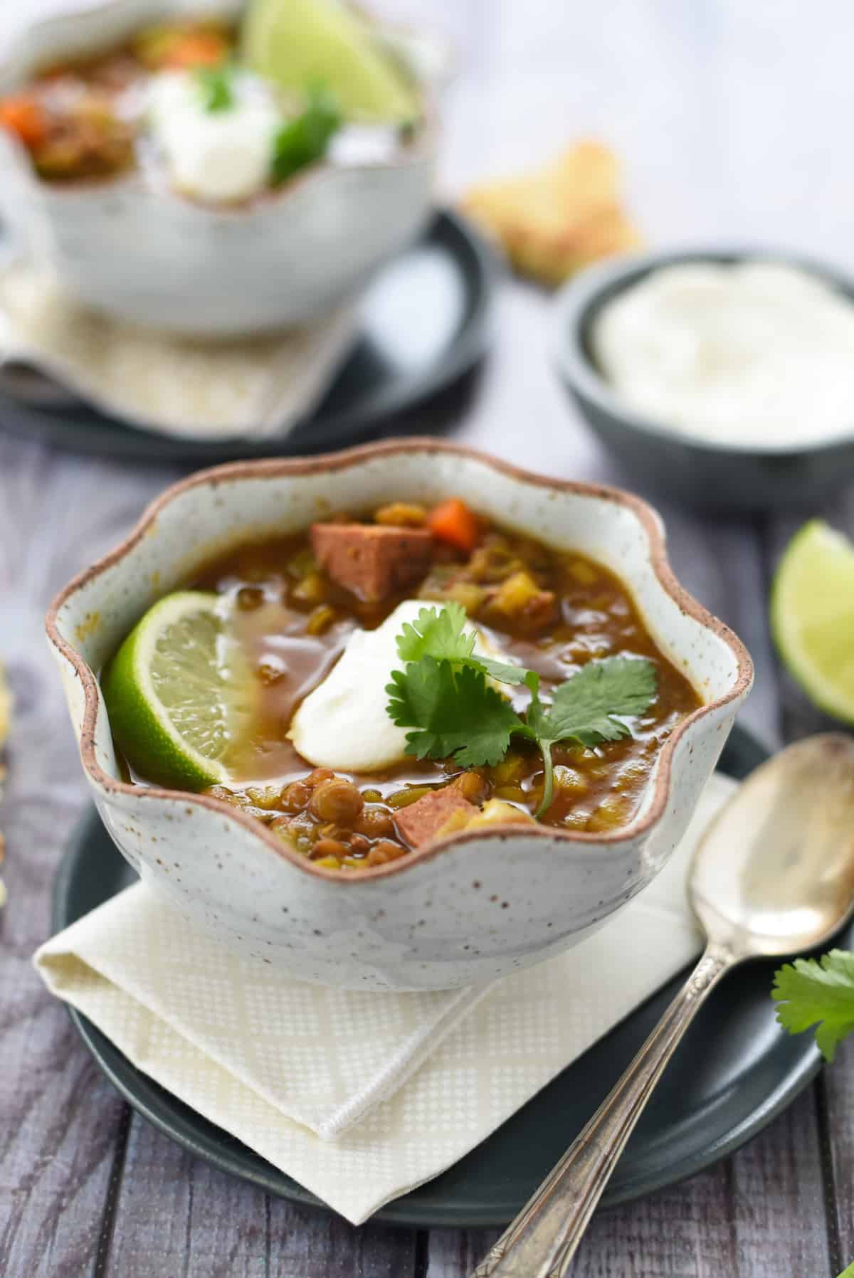This Instant Pot Lentil Soup is the absolute easiest way to get a tasty, healthy meal on the table in minutes. Put everything directly into your pressure cooker (no sautéing necessary) and cook for 15 minutes. | foxeslovelemons.com Pressure cooker lentil and sausage soup in a rustic bowl with spoon next to it.