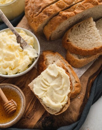 Bread spread with homemade butter on a rustic wooden cutting board.