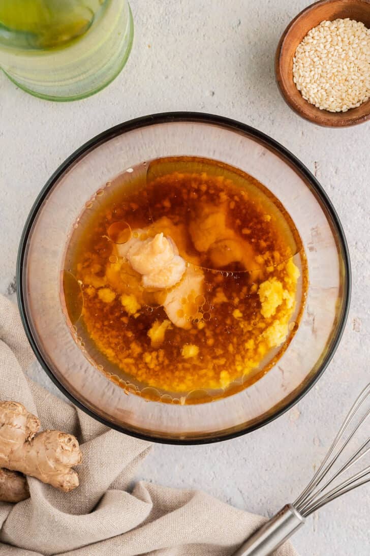 A glass bowl with the unmixed ingredients for Asian vinaigrette in it.