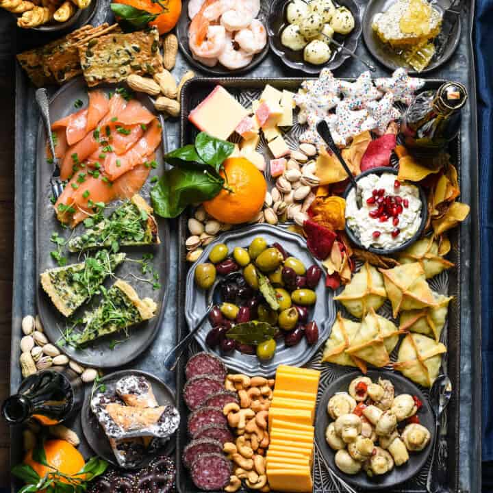 Platter filled with New Year's appetizers, including shrimp, cheese, cookies, wontons, cannoli and quiche.