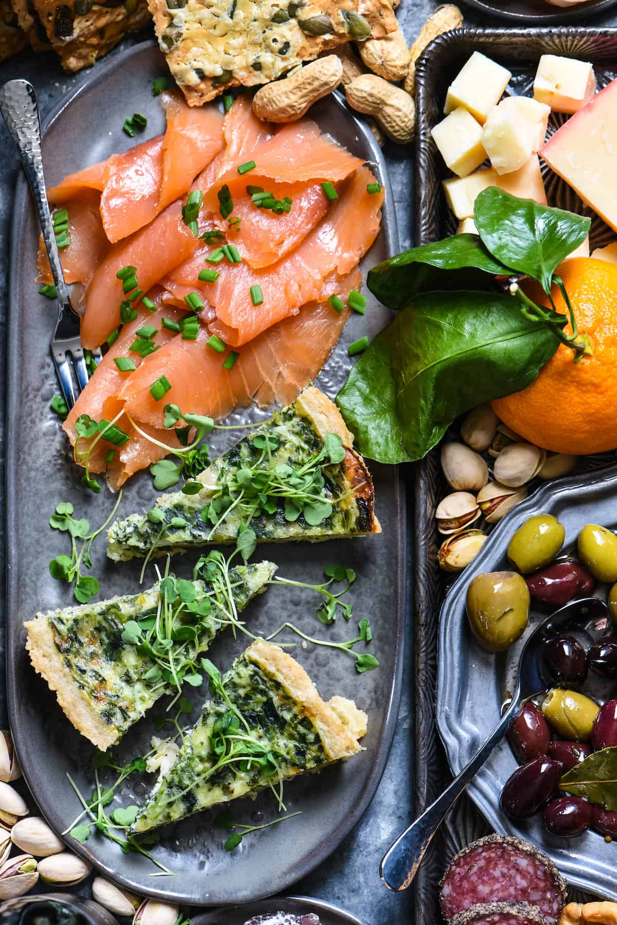 Closeup on platter of New Year's Eve appetizers focusing on slices of spinach quiche and smoked salmon.