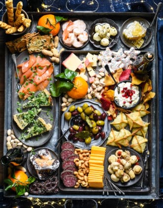 Platter filled with New Year's Eve snacks, including shrimp, cheese, cookies, wontons, cannoli and quiche.