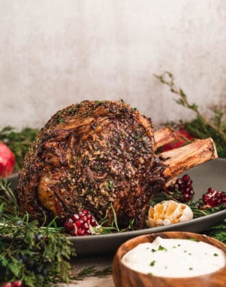 A standing rib roast covered in prime rib rub in a festive holiday dinner table scene.