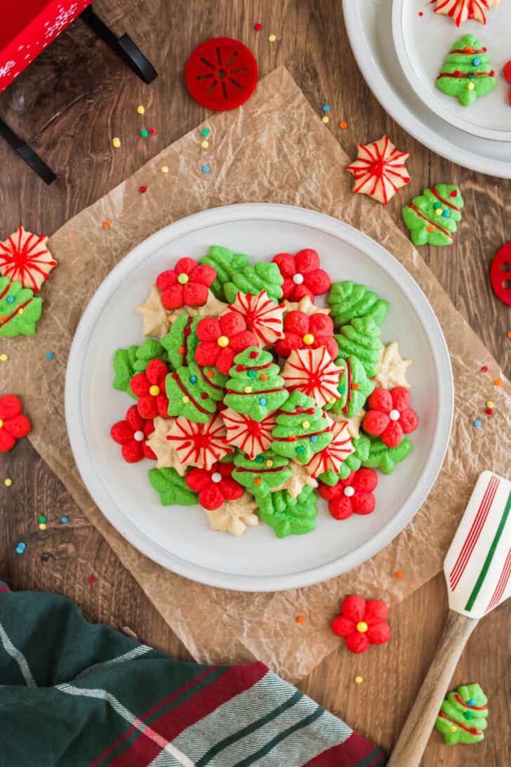 A white plate topped with red, green and white spritz cookies decorated with icing and sprinkles.