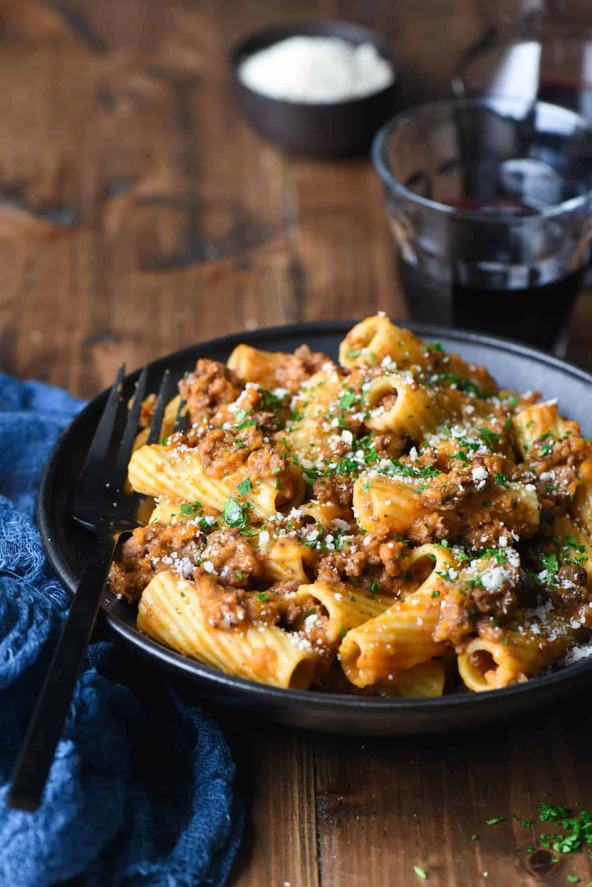 A bowl of this Rigatoni Bolognese will hit the spot whenever you have a pasta craving. This easy but elegant meat sauce recipe will give you a restaurant quality dish right at home. | foxeslovelemons.com Black bowl filled with rigatoni alla bolognese, with black fork digging in.
