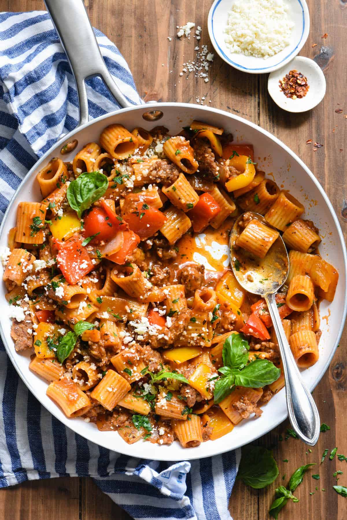 This Italian Sausage Pasta Skillet Dinner is a comforting yet veggie-packed meal that is made from start to finish in JUST ONE SKILLET. | foxeslovelemons.com A white skillet filled with an Italian sausage pasta recipe topped with fresh herbs.