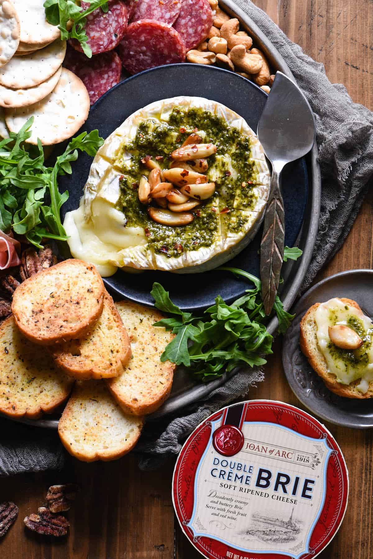 Everybody loves melted cheese, and this Savory Baked Brie takes it to the next level. Baked brie is topped with basil pesto and roasted garlic. | foxeslovelemons.com