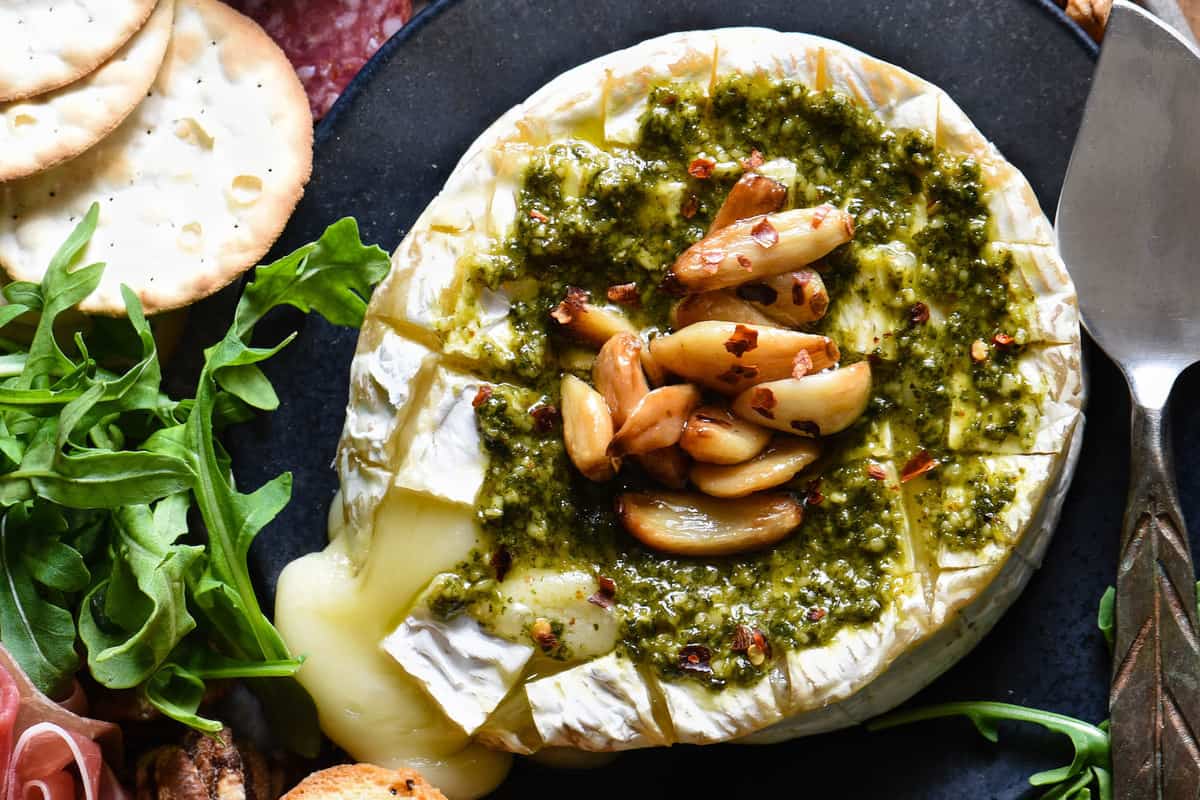 Everybody loves melted cheese, and this Savory Baked Brie takes it to the next level. Baked brie is topped with basil pesto and roasted garlic. | foxeslovelemons.com