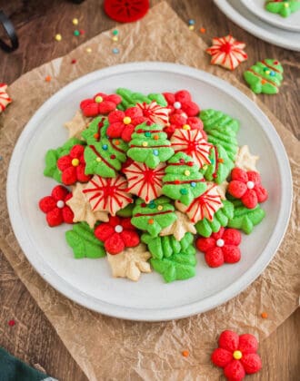 A white plate topped with red, green and white spritz cookies decorated with icing and sprinkles.