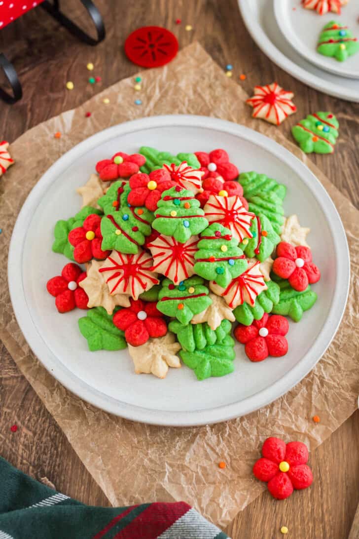 A white plate topped with red, green and white spritz cookies decorated with icing and sprinkles.