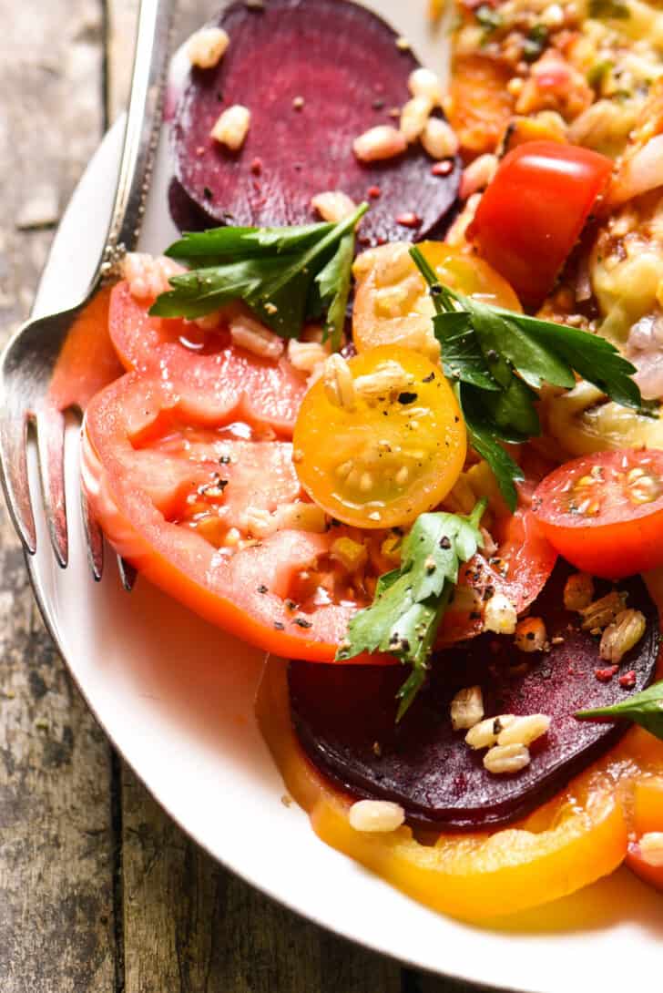 Closeup on tomato beet salad on a plate with a fork.