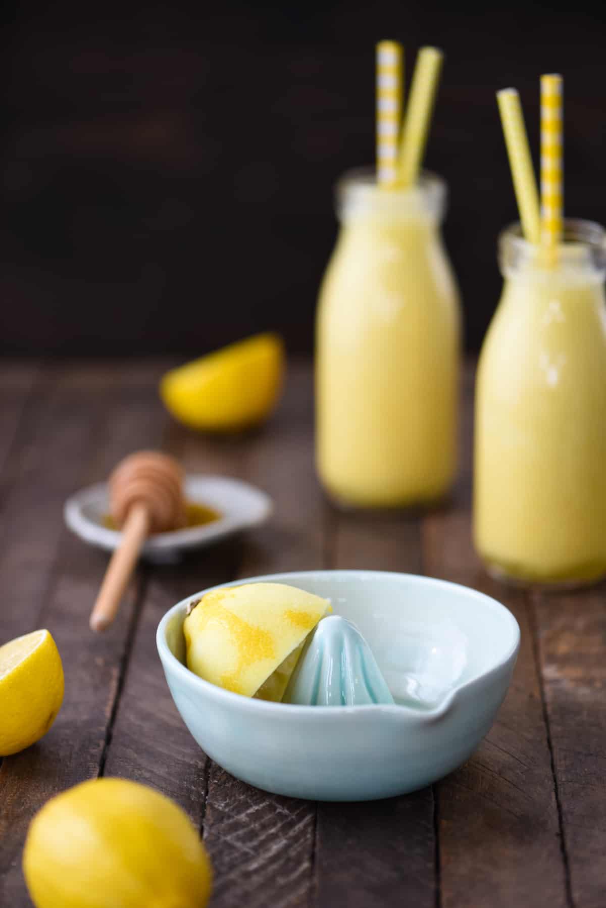 This Lemon Smoothie is like sunshine in a bottle! Yogurt, lemon, honey, ginger and turmeric will wake you up on a sleepy morning. | foxeslovelemons.com A small light blue ceramic lemon juicer bowl with a lemon half in it.