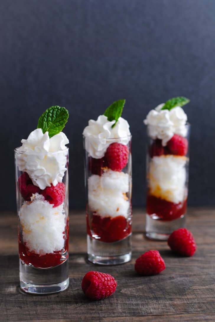 An easy Valentine's dessert made in three tall shot glasses, with layers of cake, raspberries, red jam and whipped cream.