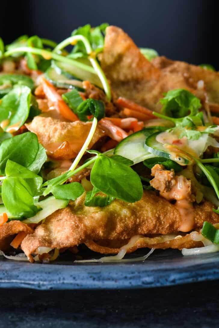 Asian nachos made from crispy wonton chips, ground pork, pickled veggies, herbs and spicy mayo.